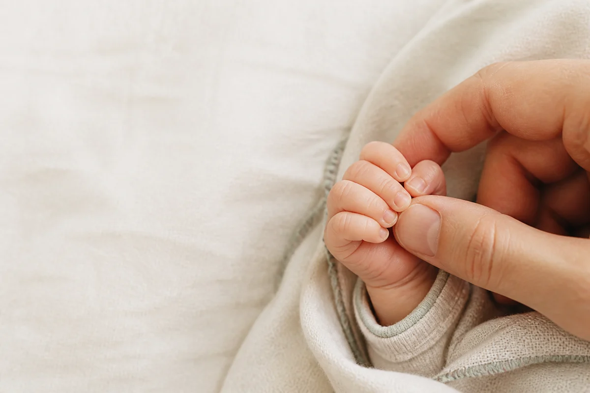 Младенец держит палец родителя